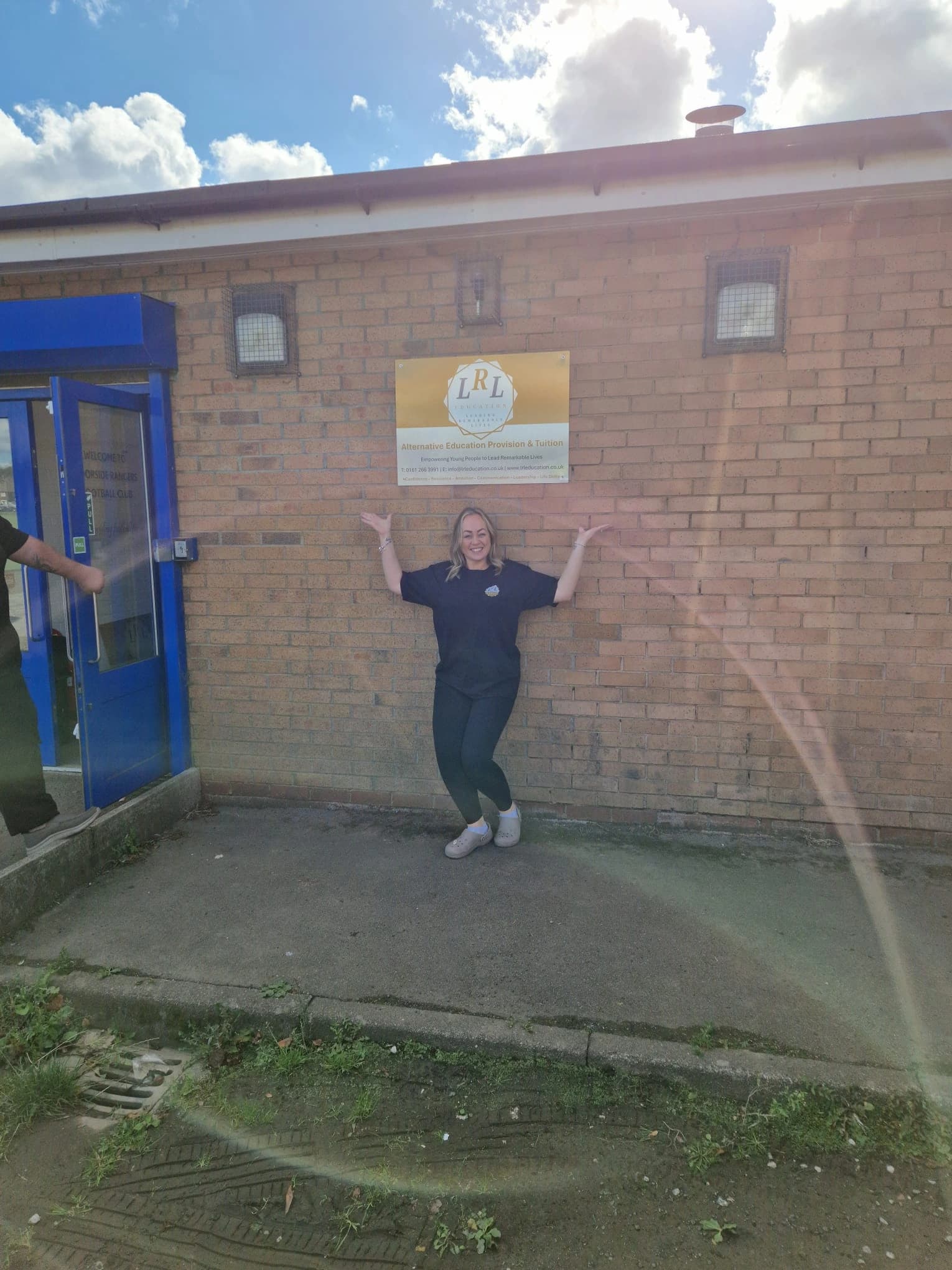 An LRL Education staff member standing beneath the Salford provision sign.